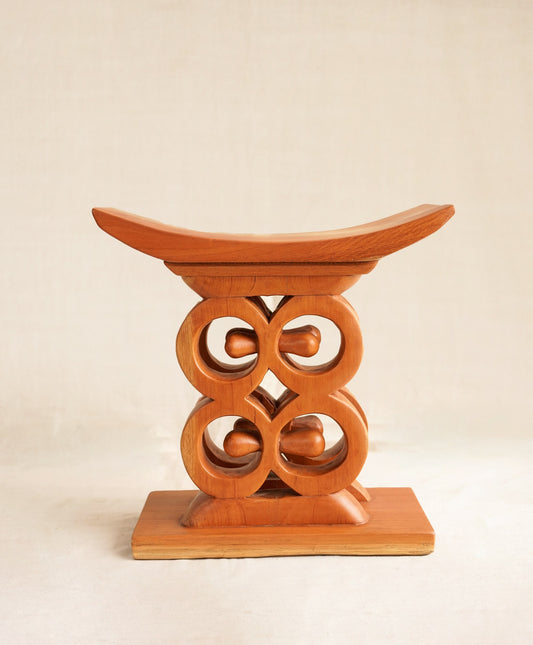 Wooden stool with intricate carvings on a beige background