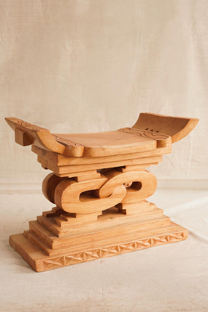 Wooden stool with intricate carvings on a plain background