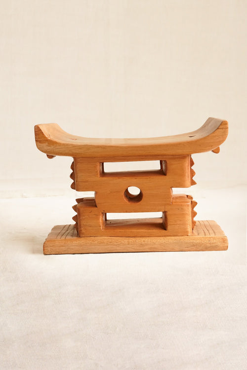 Wooden stool with a traditional design on a beige background