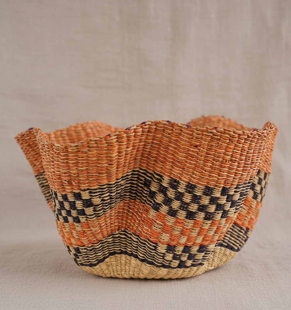Woven basket with orange and black pattern on a white background