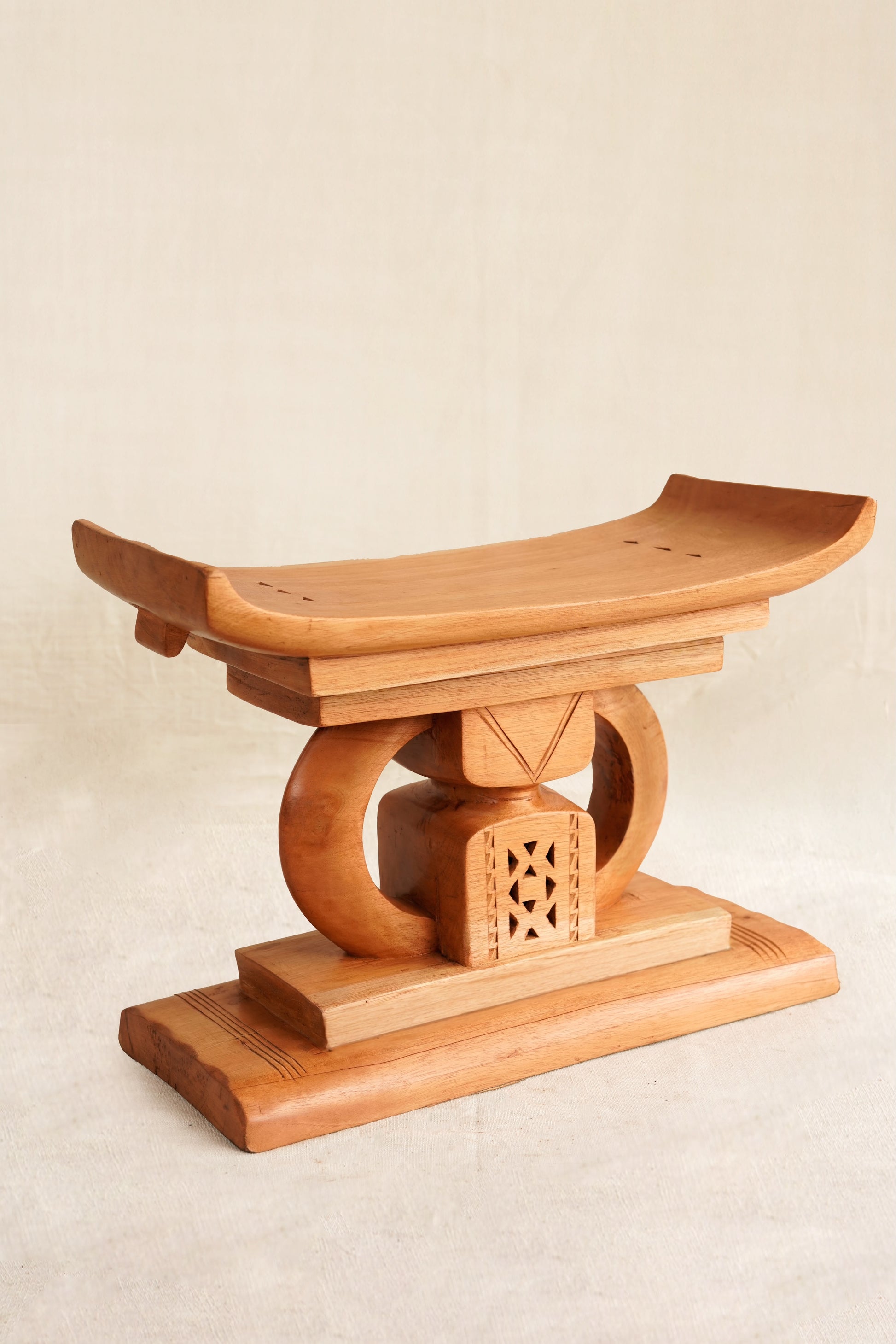 Wooden stool with intricate design on a beige background