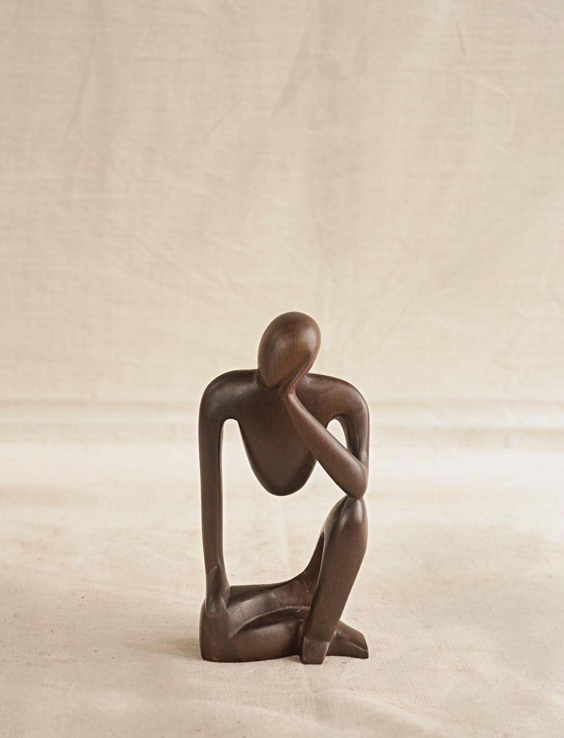 Abstract sculpture of a human figure on a plain background