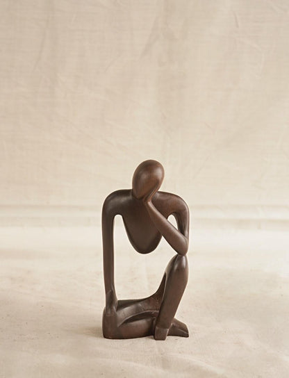 Abstract sculpture of a human figure on a plain background