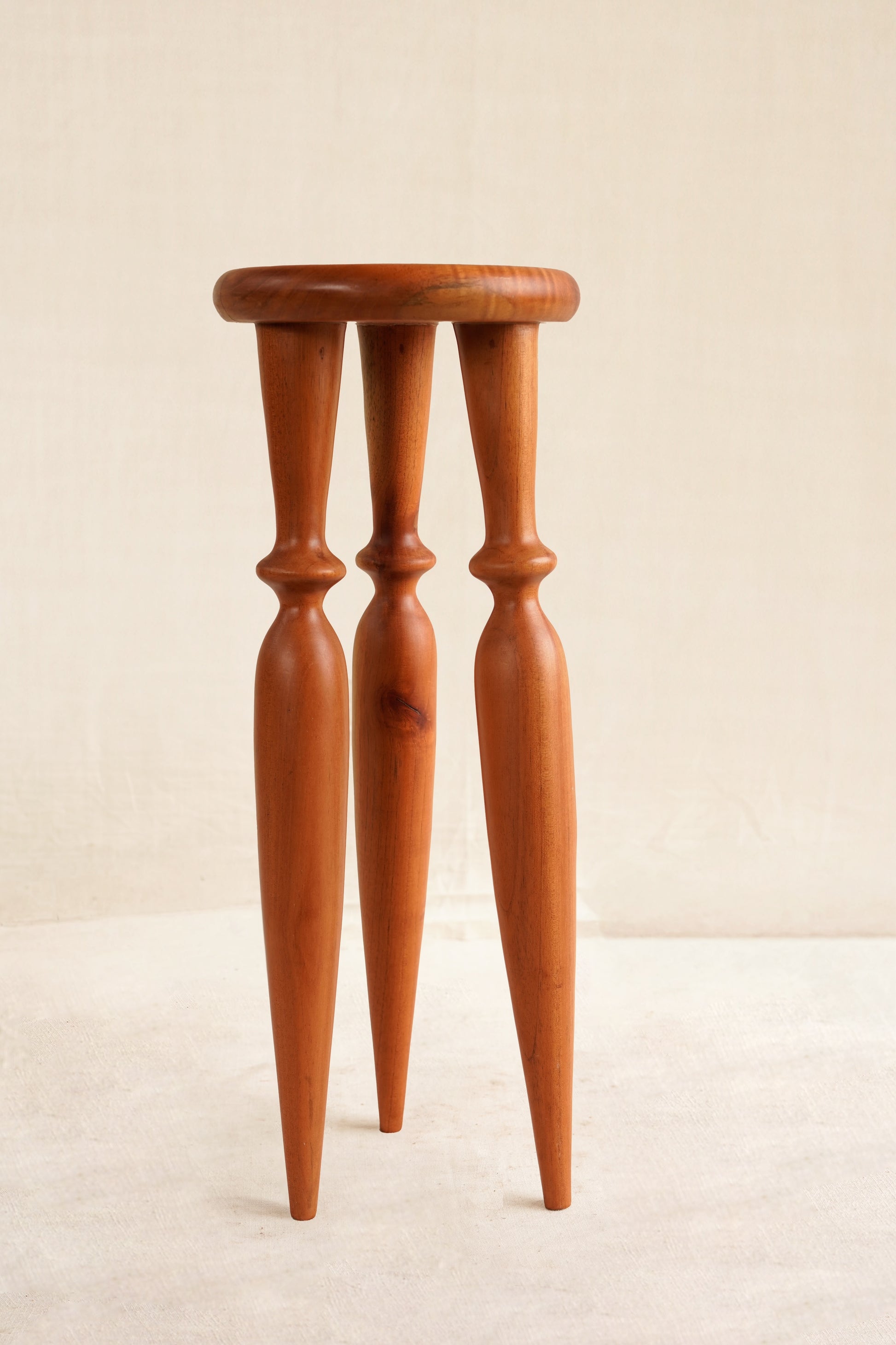Wooden stool with four thin legs on a beige background