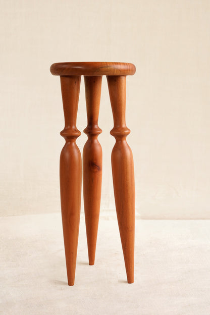 Wooden stool with four thin legs on a beige background
