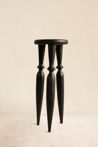Black stool with thin legs on a beige background