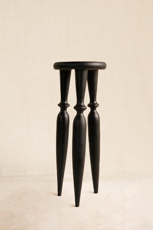 Black stool with thin legs on a beige background