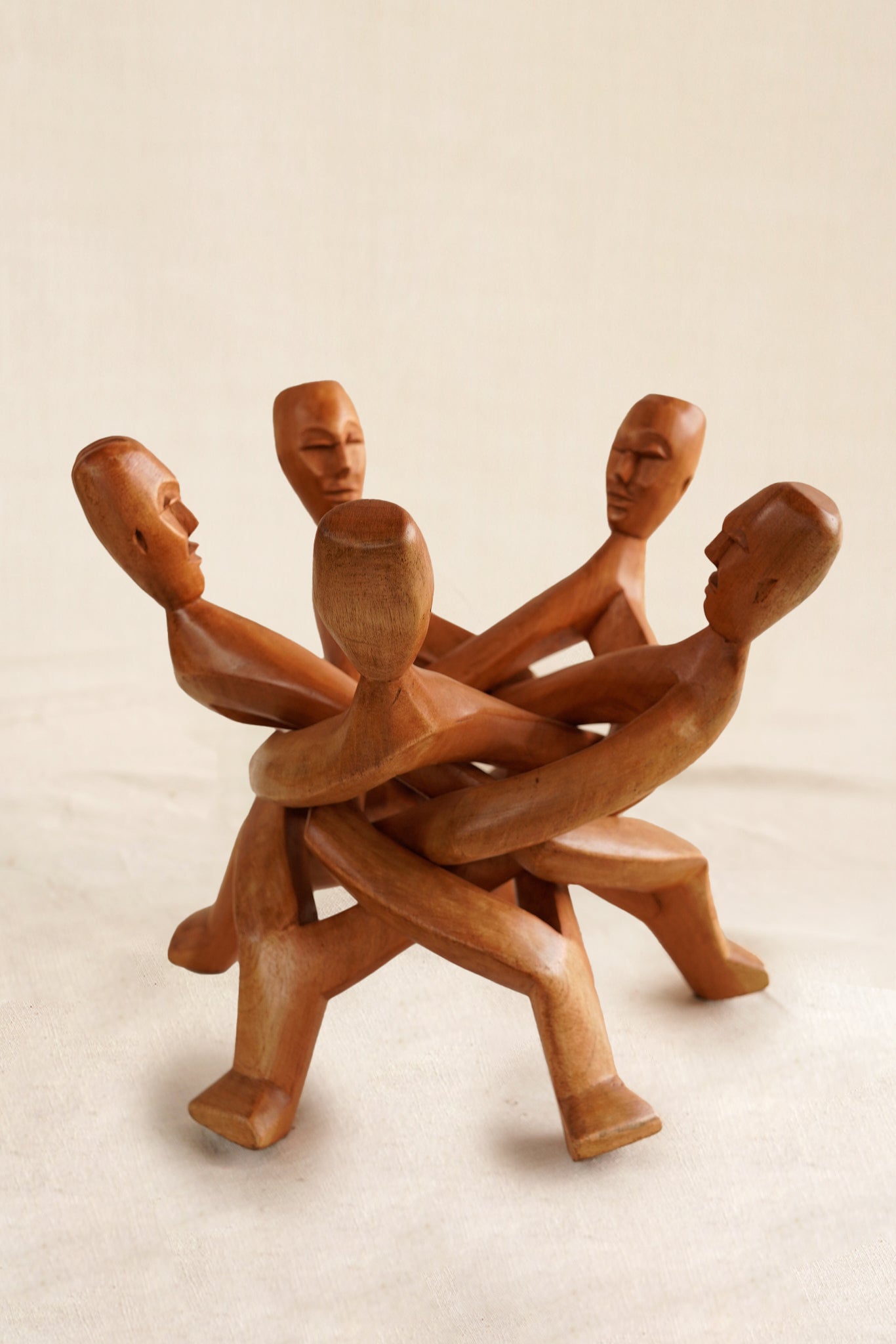 Wooden sculpture of five interlocking figures on a beige background