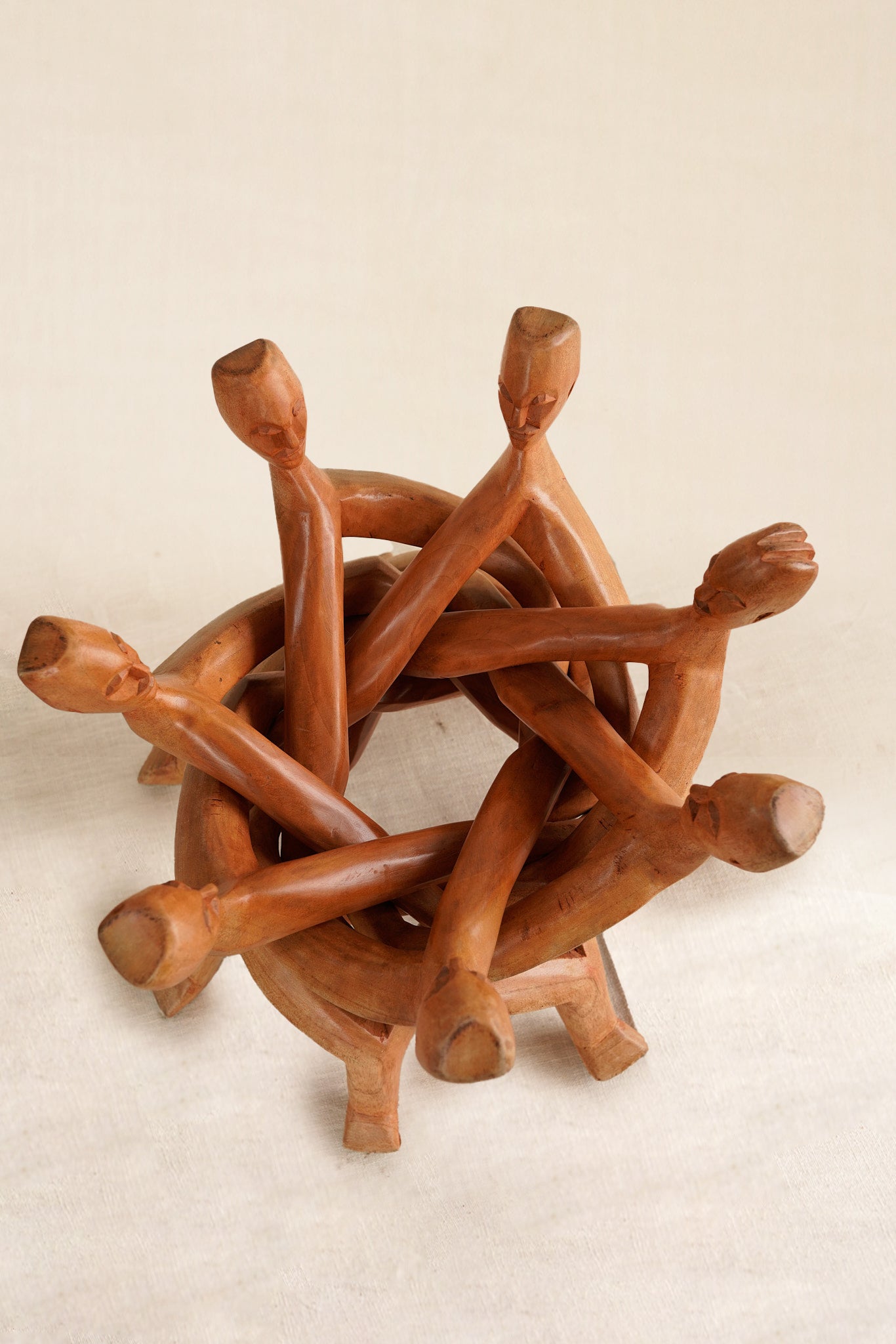 Wooden sculpture of intertwined figures on a beige background