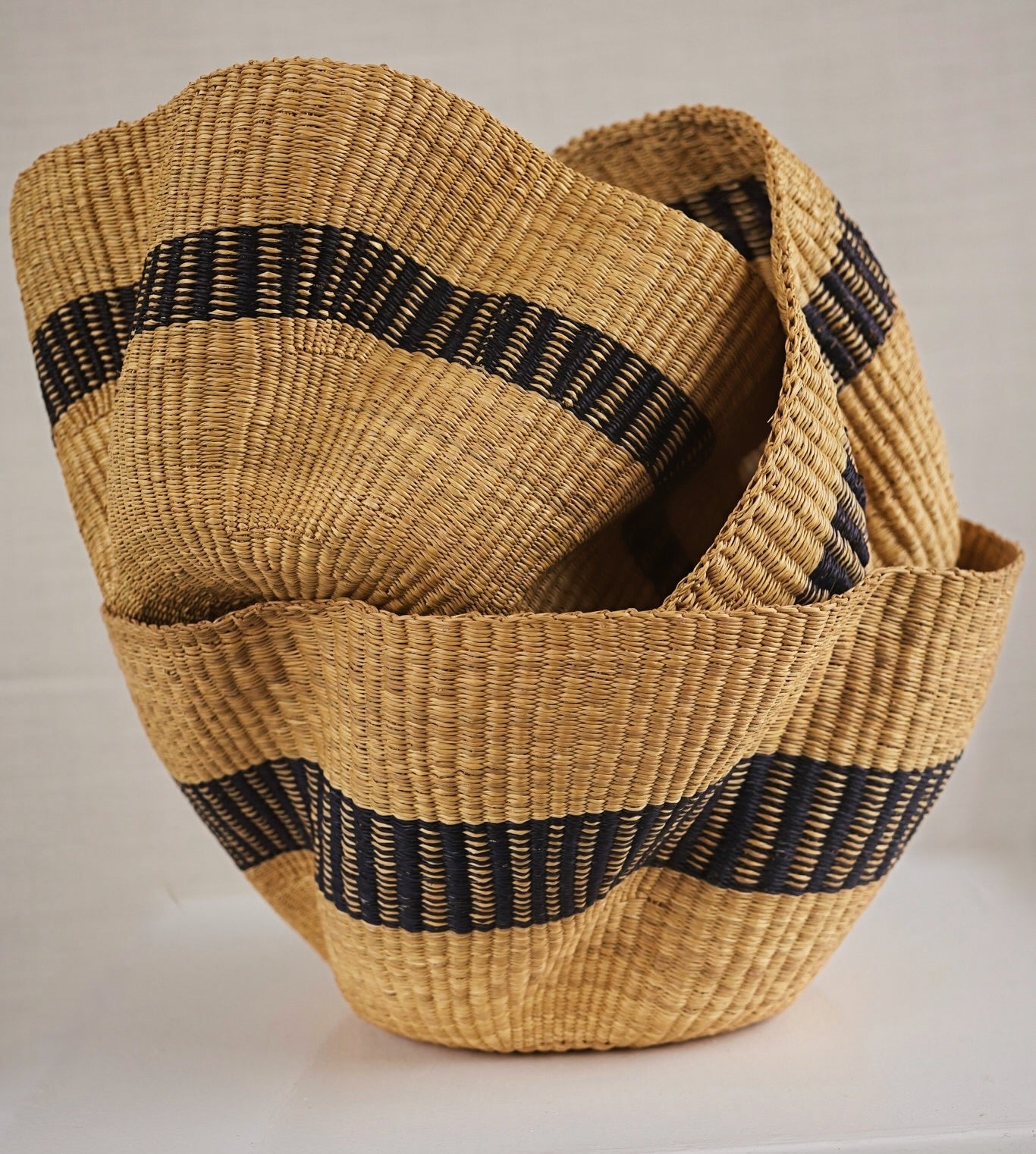 Woven basket with black straps on a light background