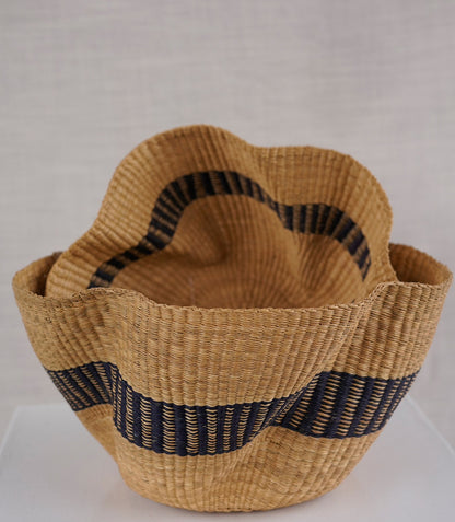 Woven basket with black striped handles on a white background