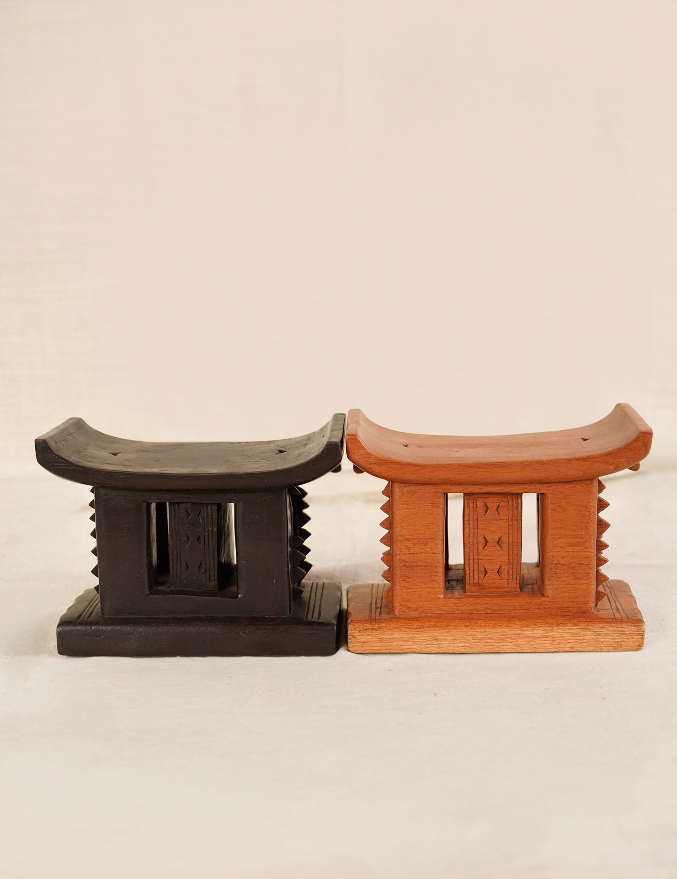 Two wooden stools, one black and one brown, on a beige background