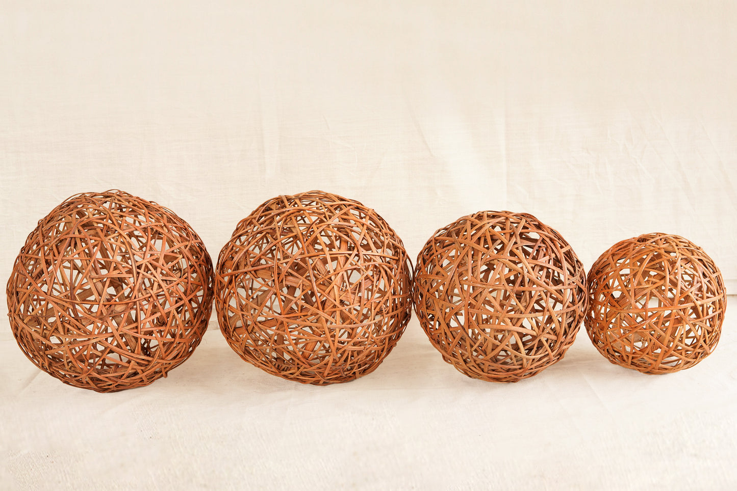 Four woven rattan balls on a beige background