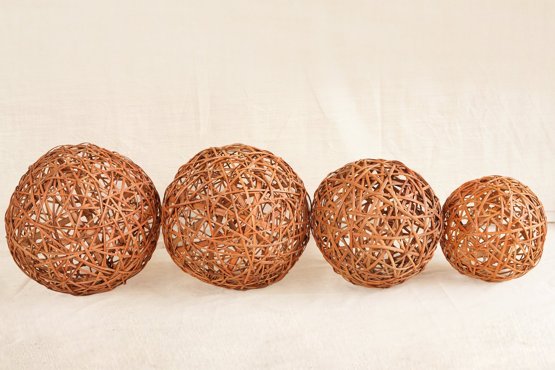 Four woven rattan balls on a beige background