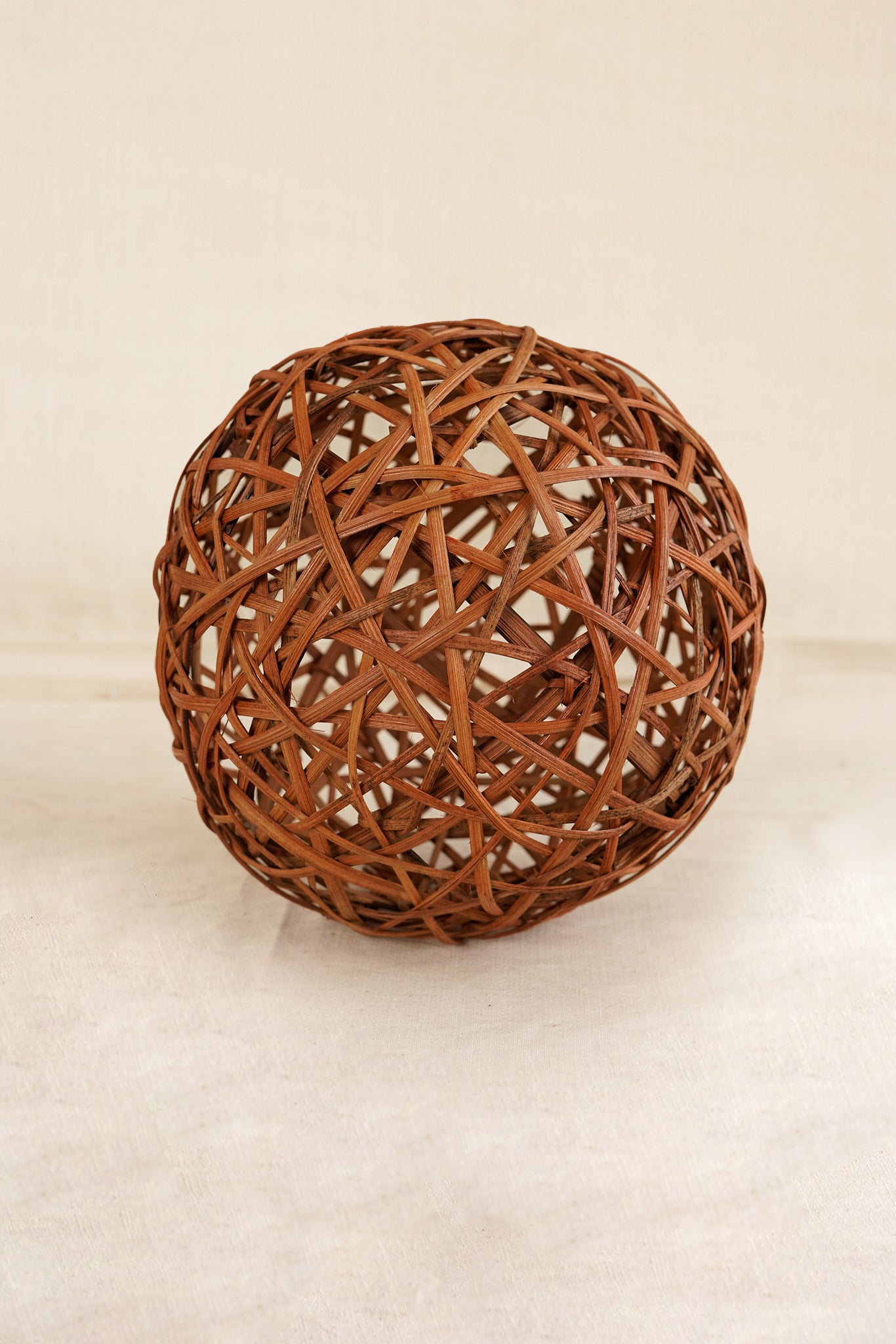Woven brown spherical object on a beige background