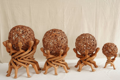 Set of four woven spherical objects on wooden stands against a neutral background